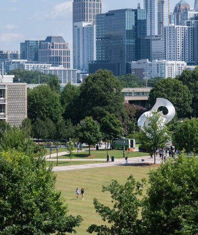 Tech Green surrounded by trees with the Midtown skyline in the background.